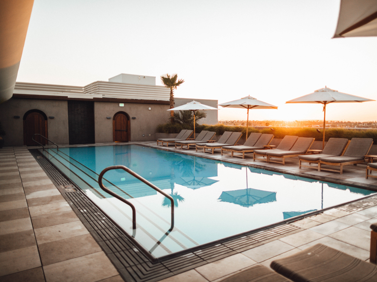 Pool with lounge chairs and umbrellas at sunset.