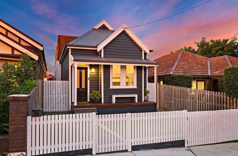 A small house with a white picket fence in front of it.