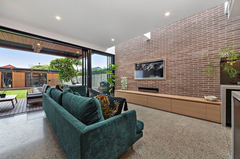 A living room with a green couch and a brick wall.