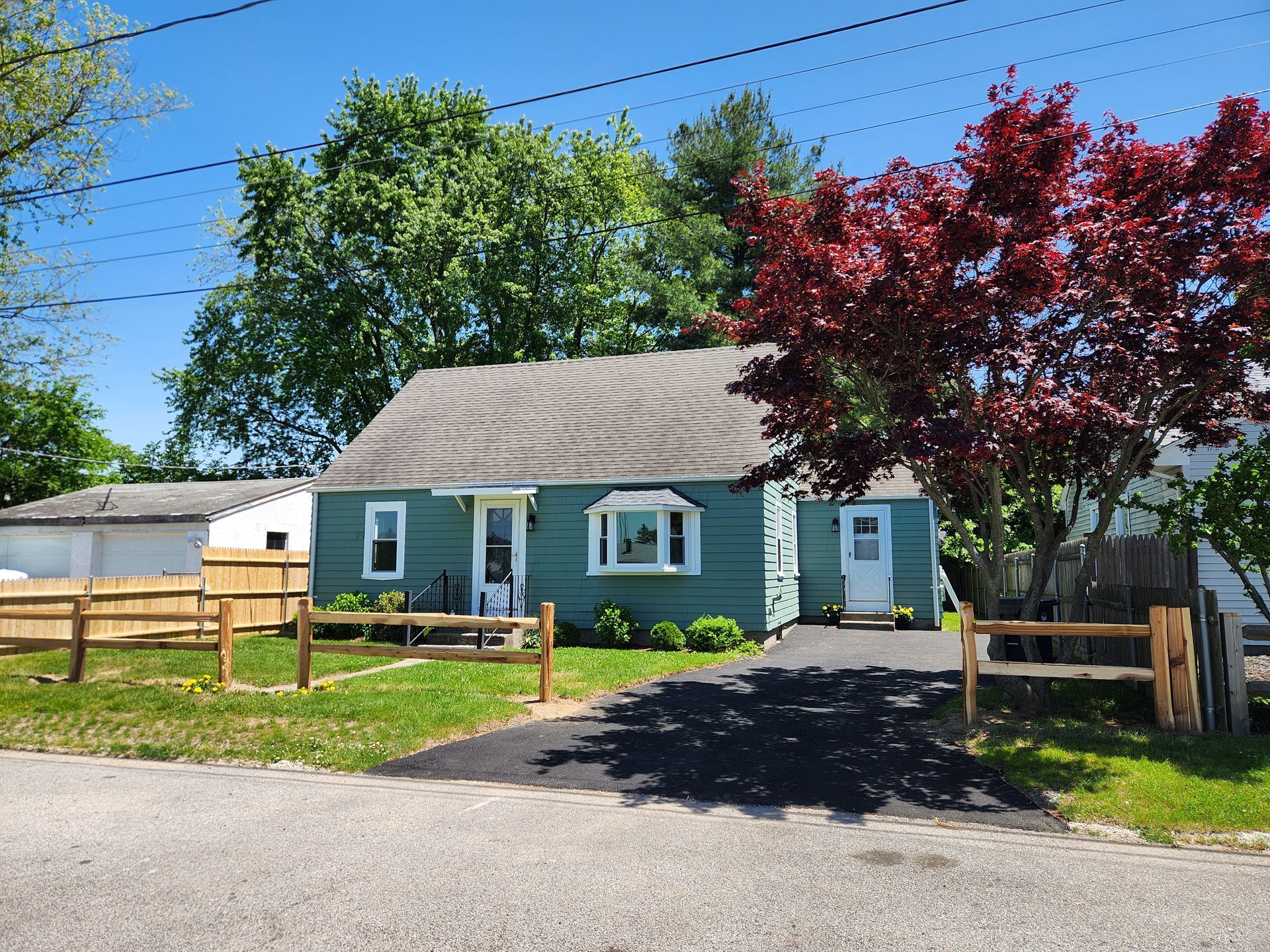 A small green house with a wooden fence in front of it