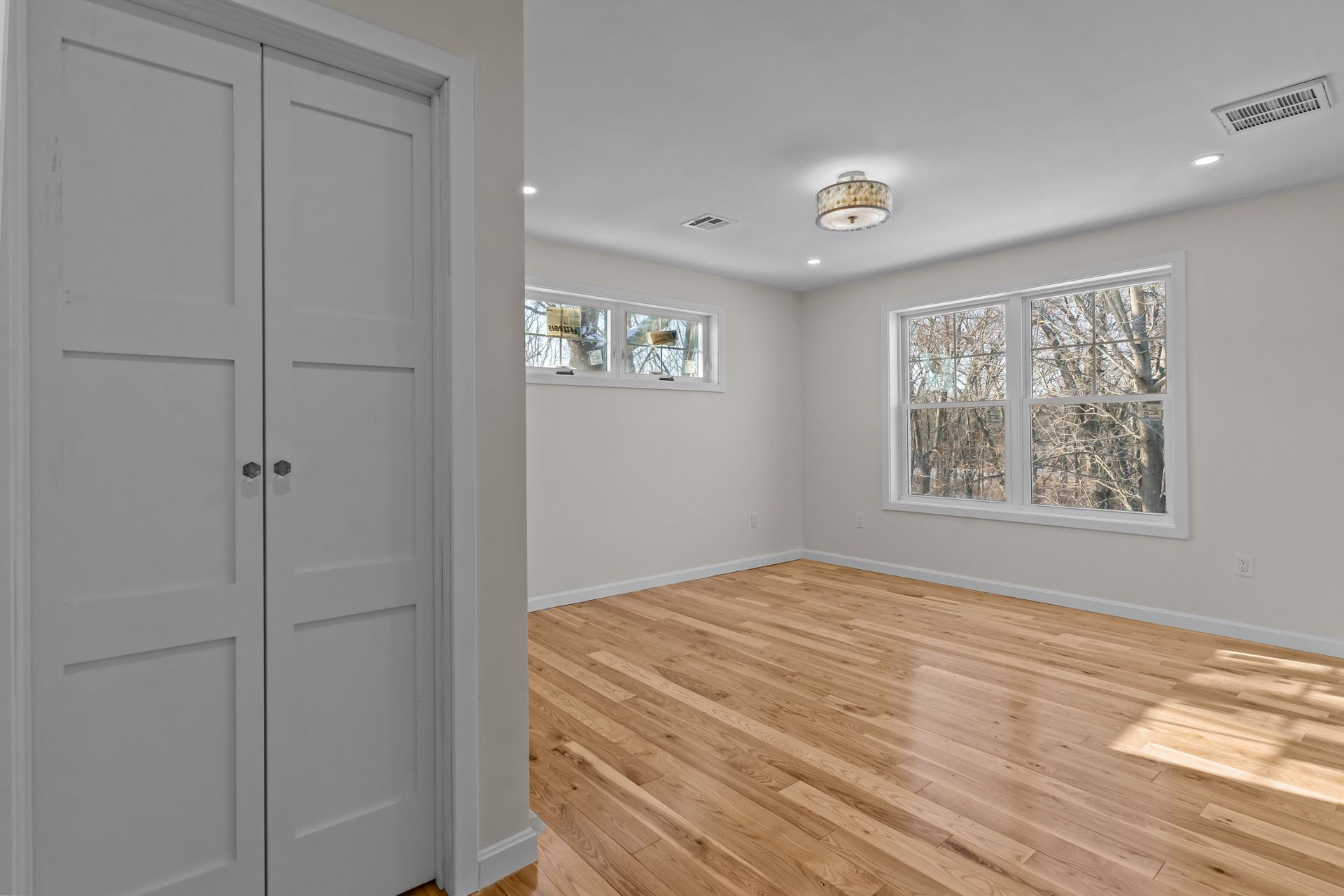 An empty room with hardwood floors and white walls.