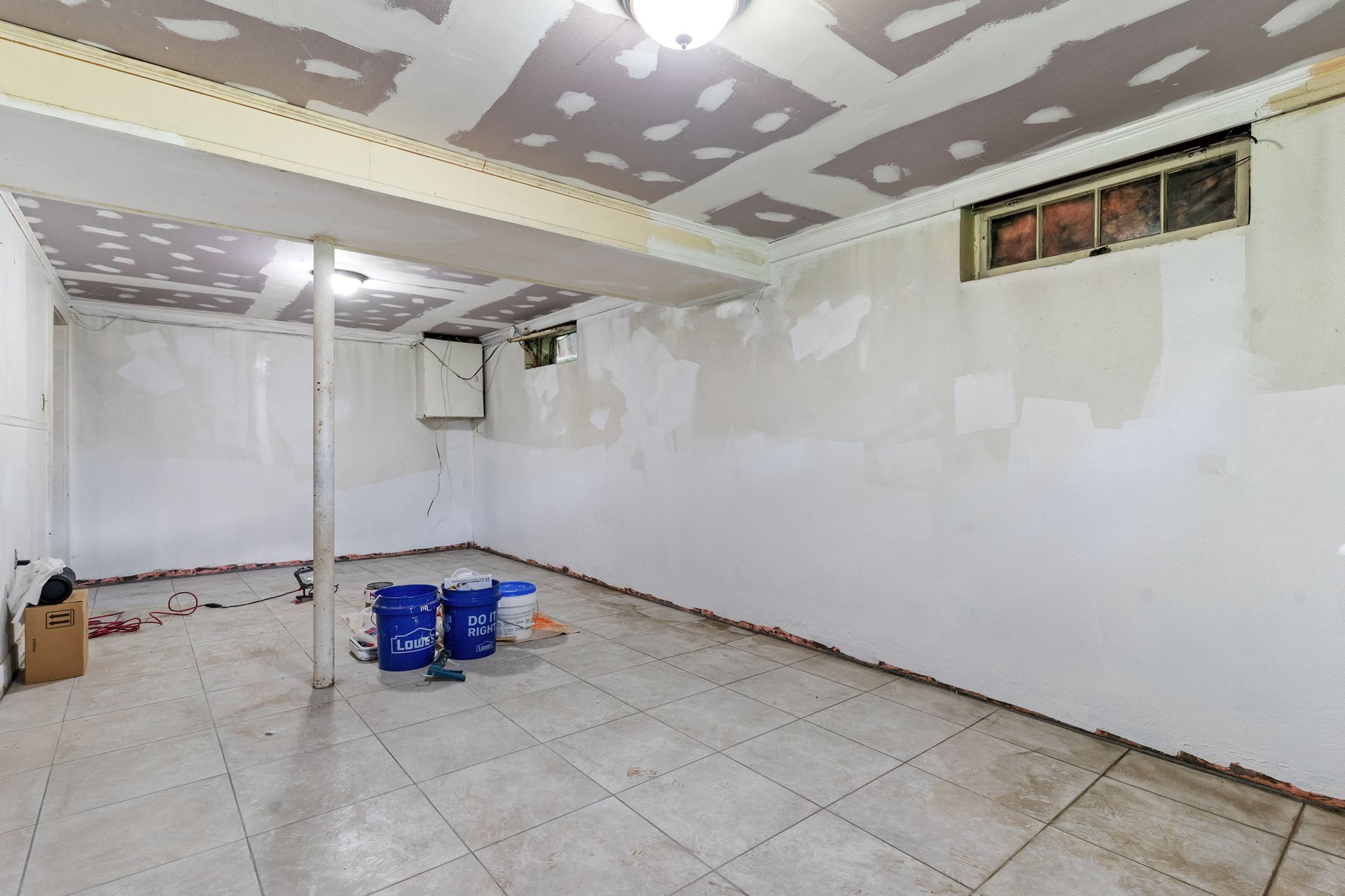 An empty basement with tile floors and white walls.