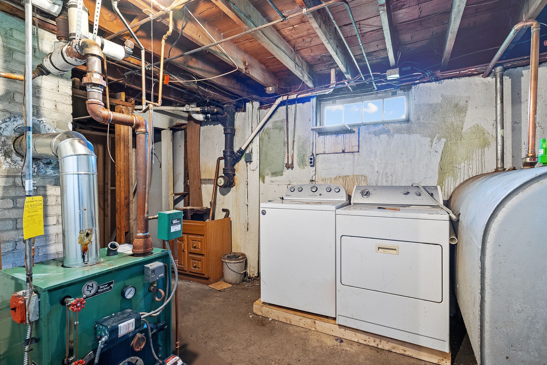 A basement with a washer and dryer and a boiler.