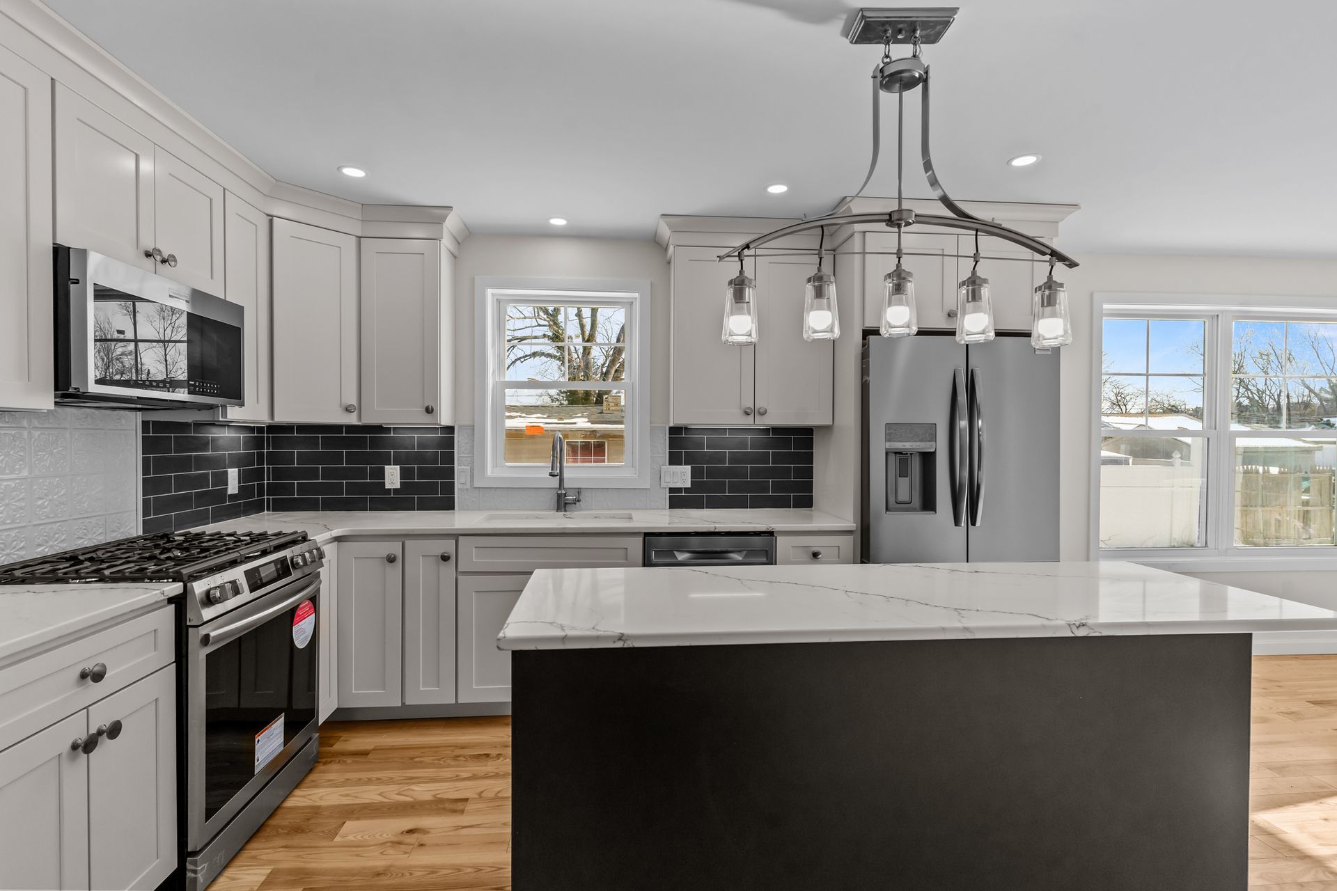 A kitchen with white cabinets , stainless steel appliances , and a large island.