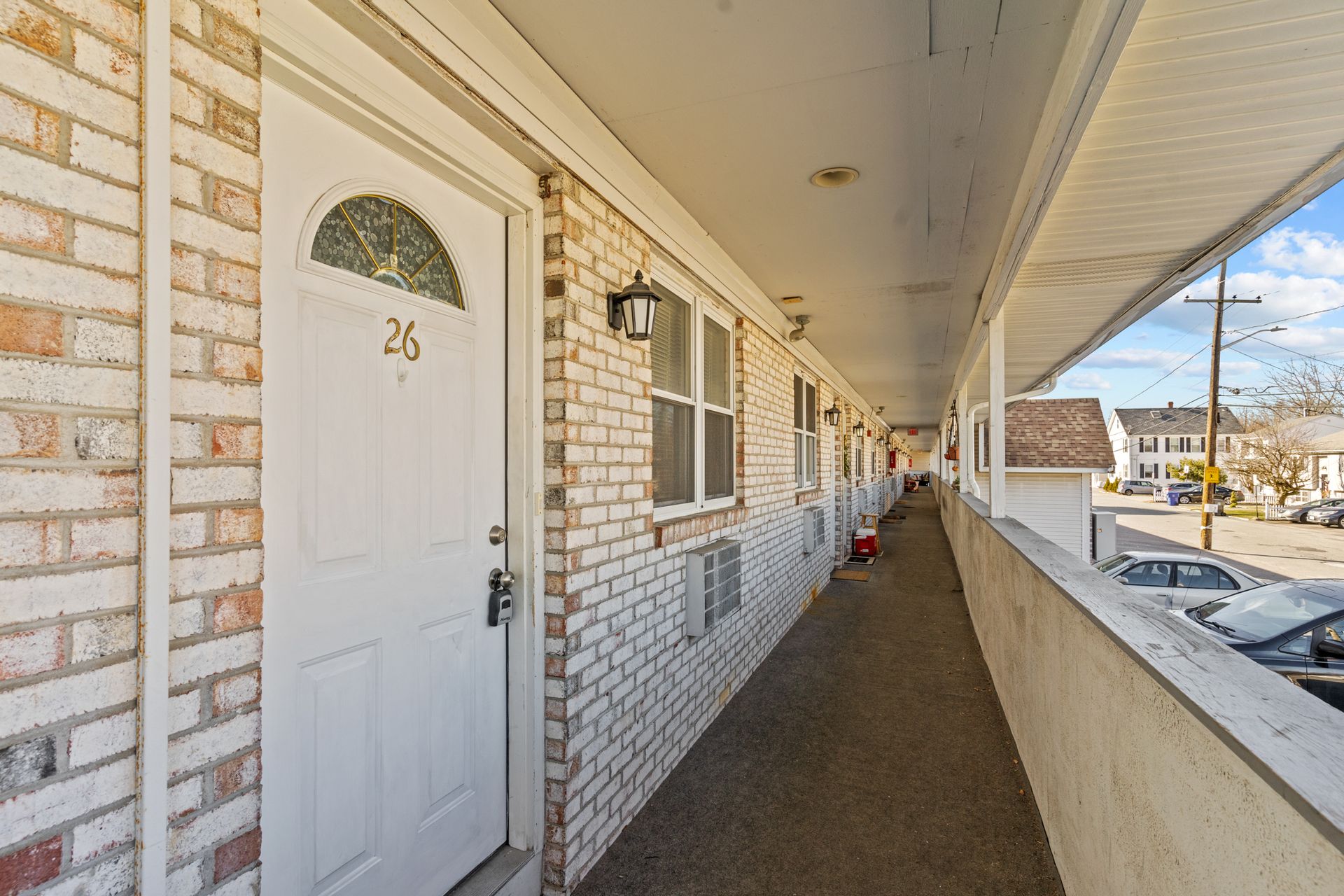 A long hallway between two buildings with brick walls and white doors.