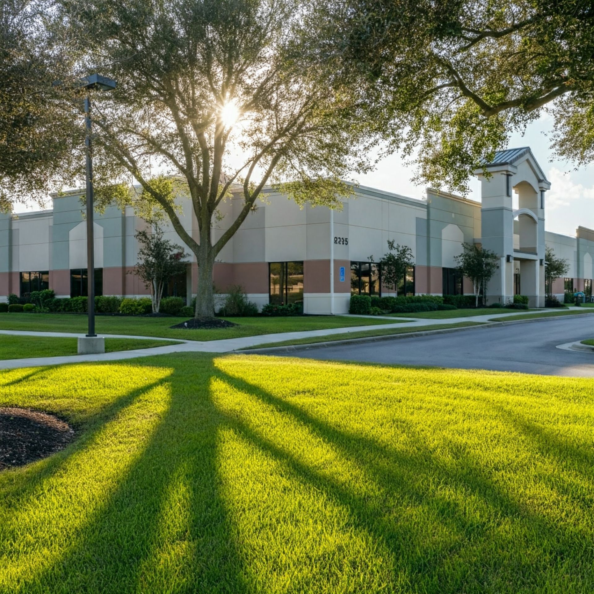 The sun is shining through the trees in front of a large building