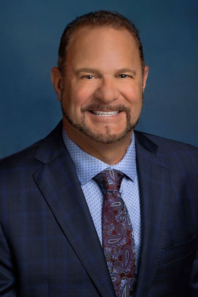 A man dressed in suit and tie smiling.