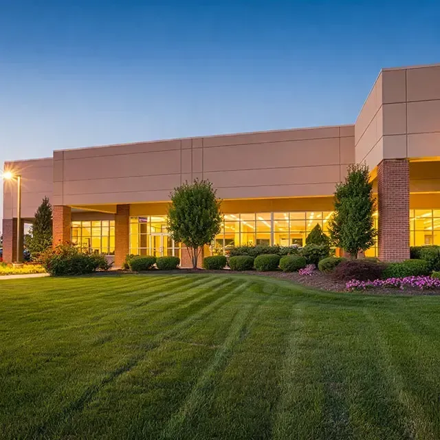 A large building with a lot of windows and a lush green lawn in front of it.