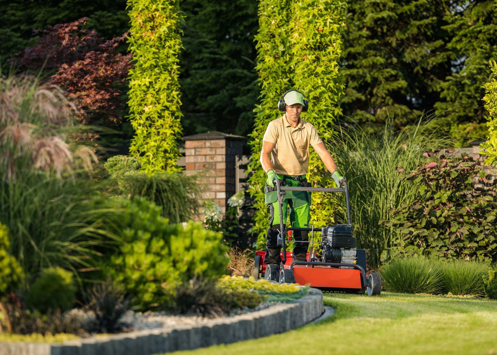 A man is mowing a lush green lawn with a lawn mower.