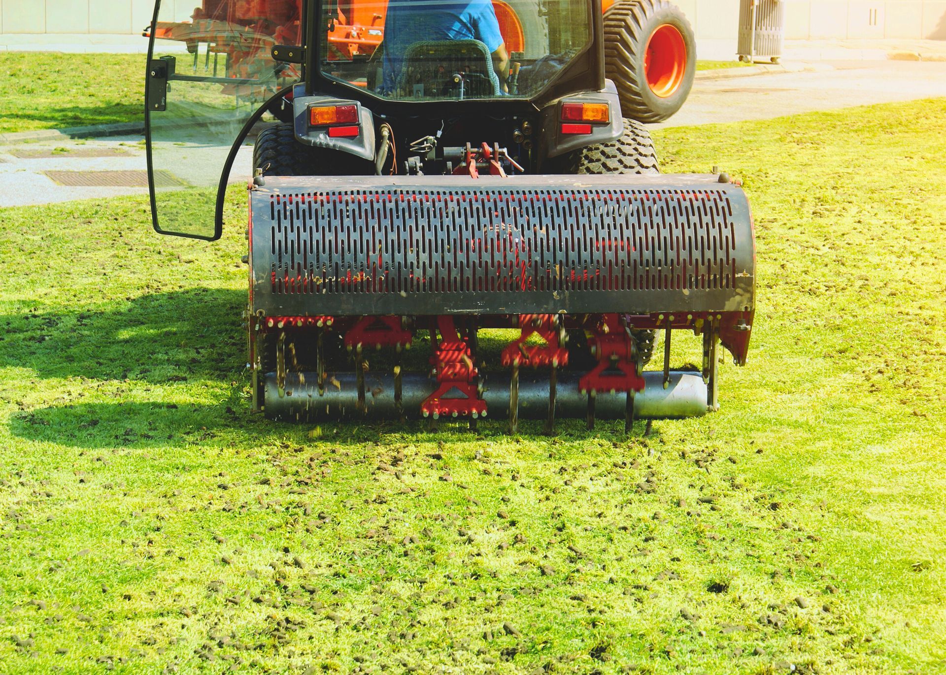 A tractor is aerating a lush green lawn.