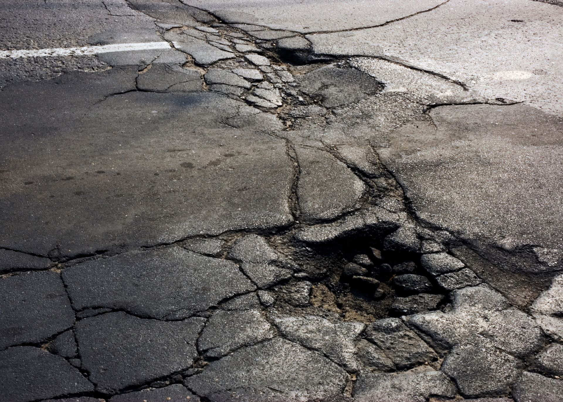 A black and white photo of a buckling parking lot in need of asphalt repair.