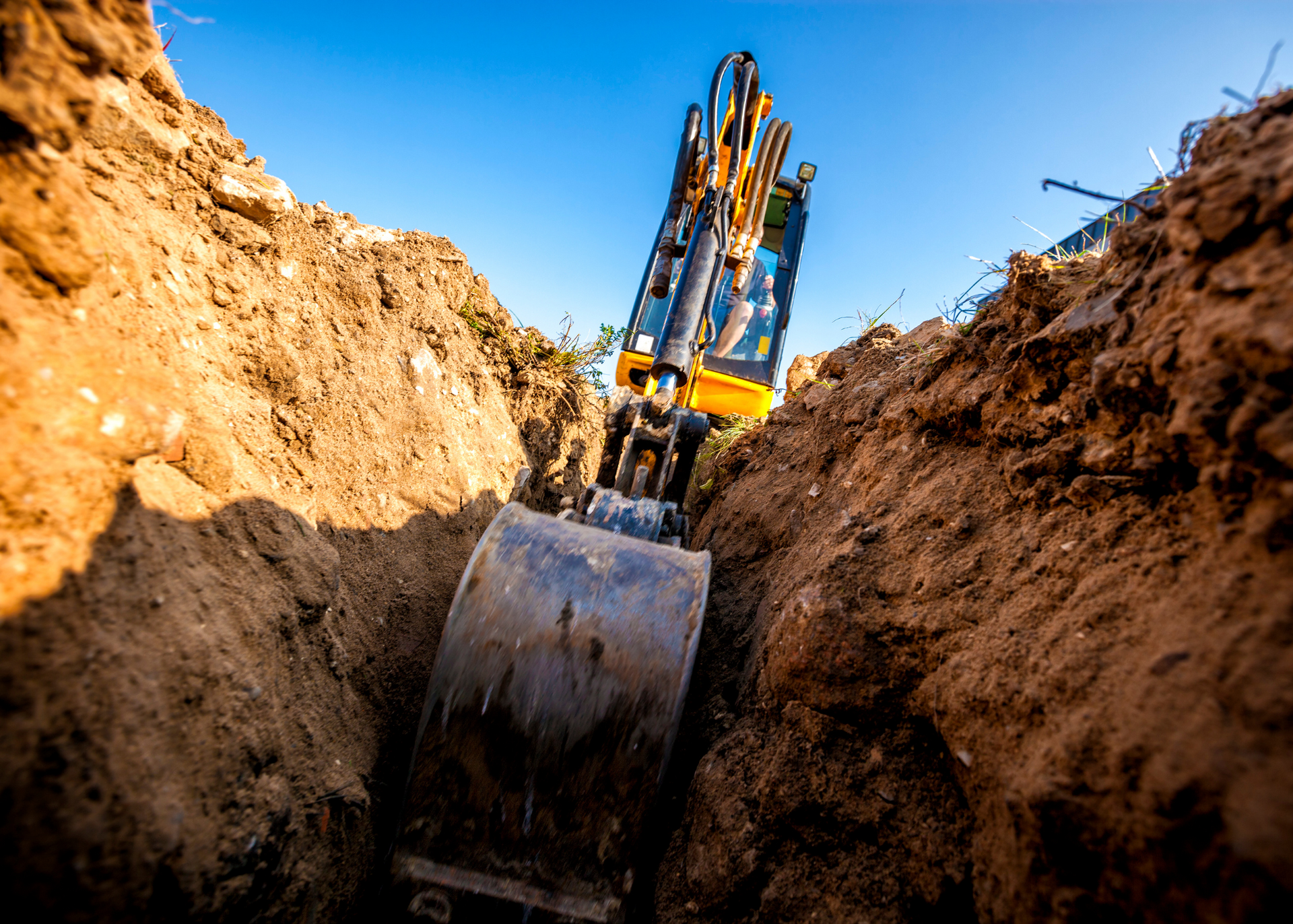 An excavator is digging a long and narrow hole for drainage pipes.