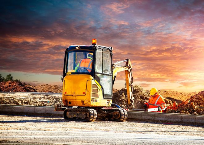 A man is driving a small excavator on a construction site.