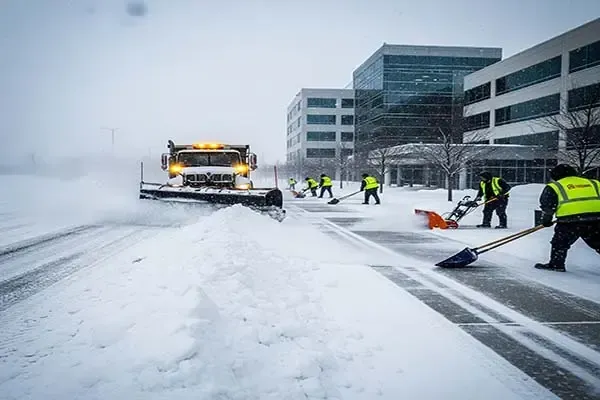 A yellow tractor is clearing snow from a parking lot.