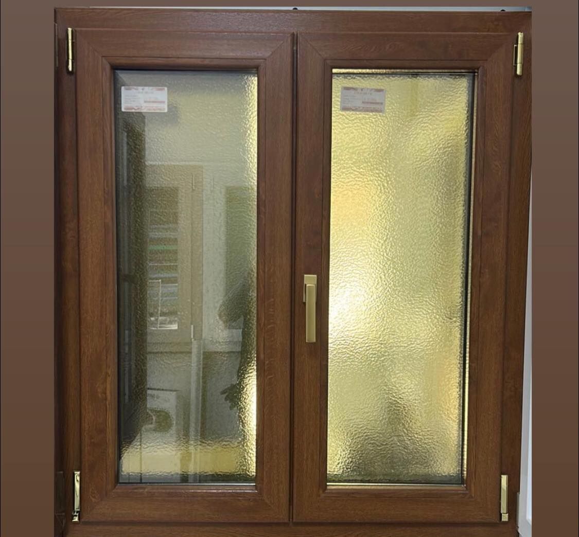 Una finestra a doppio vetro con telaio in legno marrone, composta da un vetro trasparente e un vetro testurizzato per la privacy.