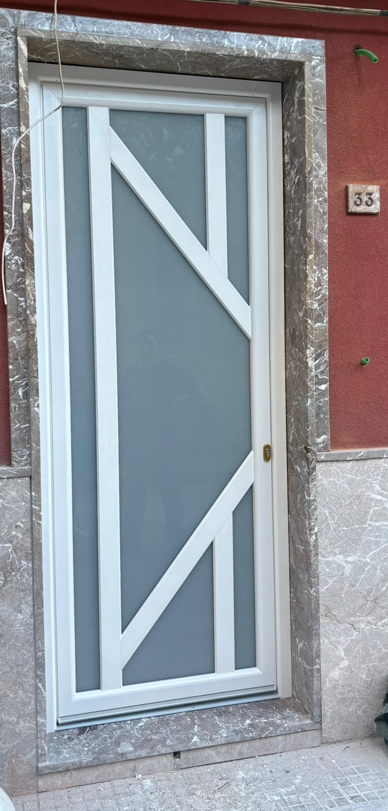 Una porta da garage grigia è parzialmente aperta, rivelando un'auto parcheggiata all'interno di un garage residenziale.