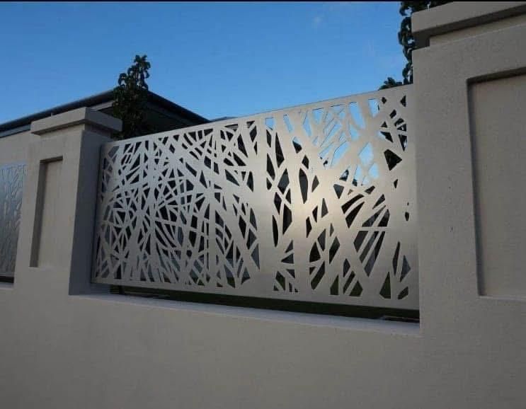 Una porta interna grigia e ruvida, incastonata in una parete bianca, con una maniglia rotonda argentata e un interruttore della luce nelle vicinanze.