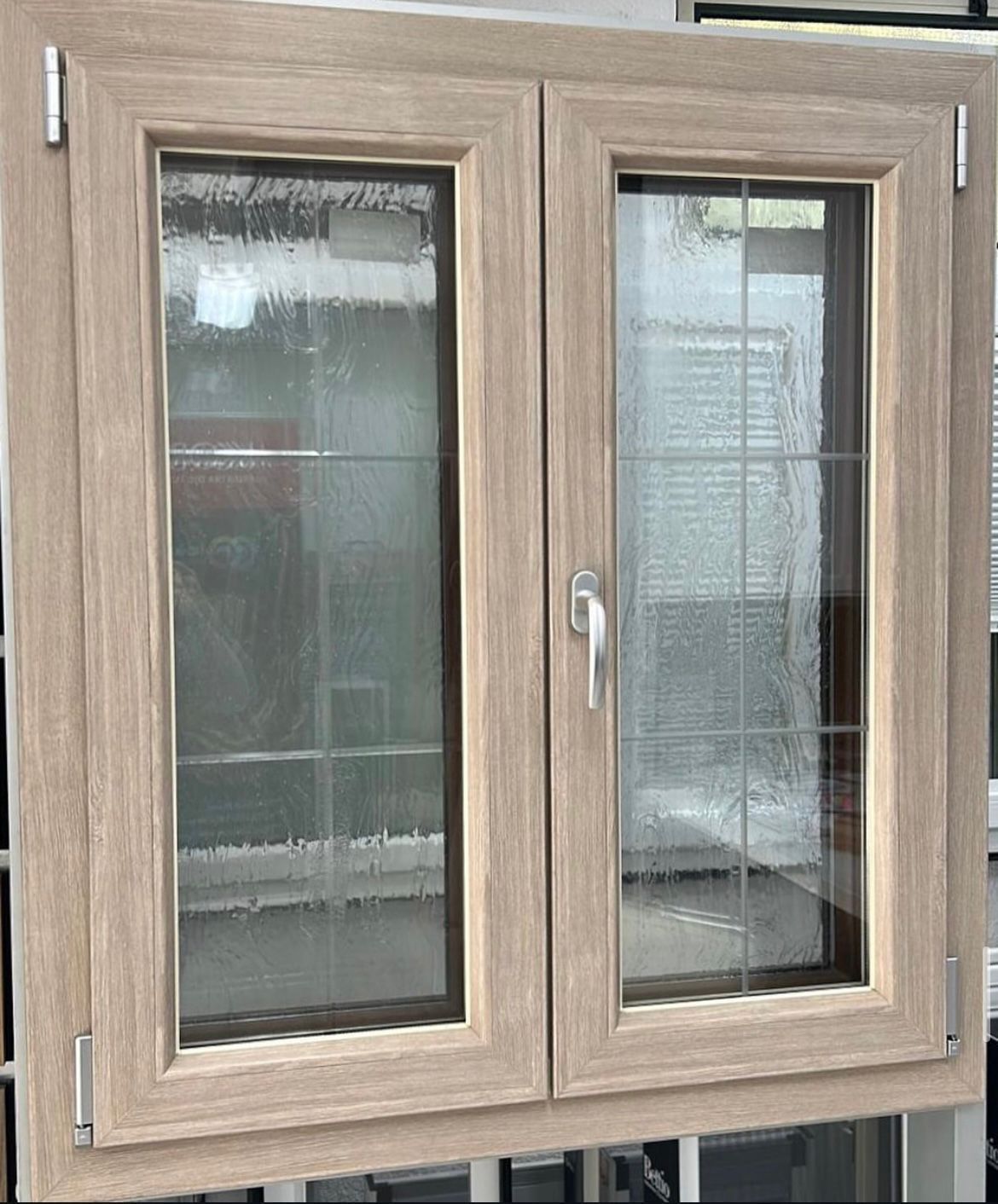 Primo piano di un telaio di finestra a doppio vetro marrone con vetro testurizzato e maniglia in ottone.