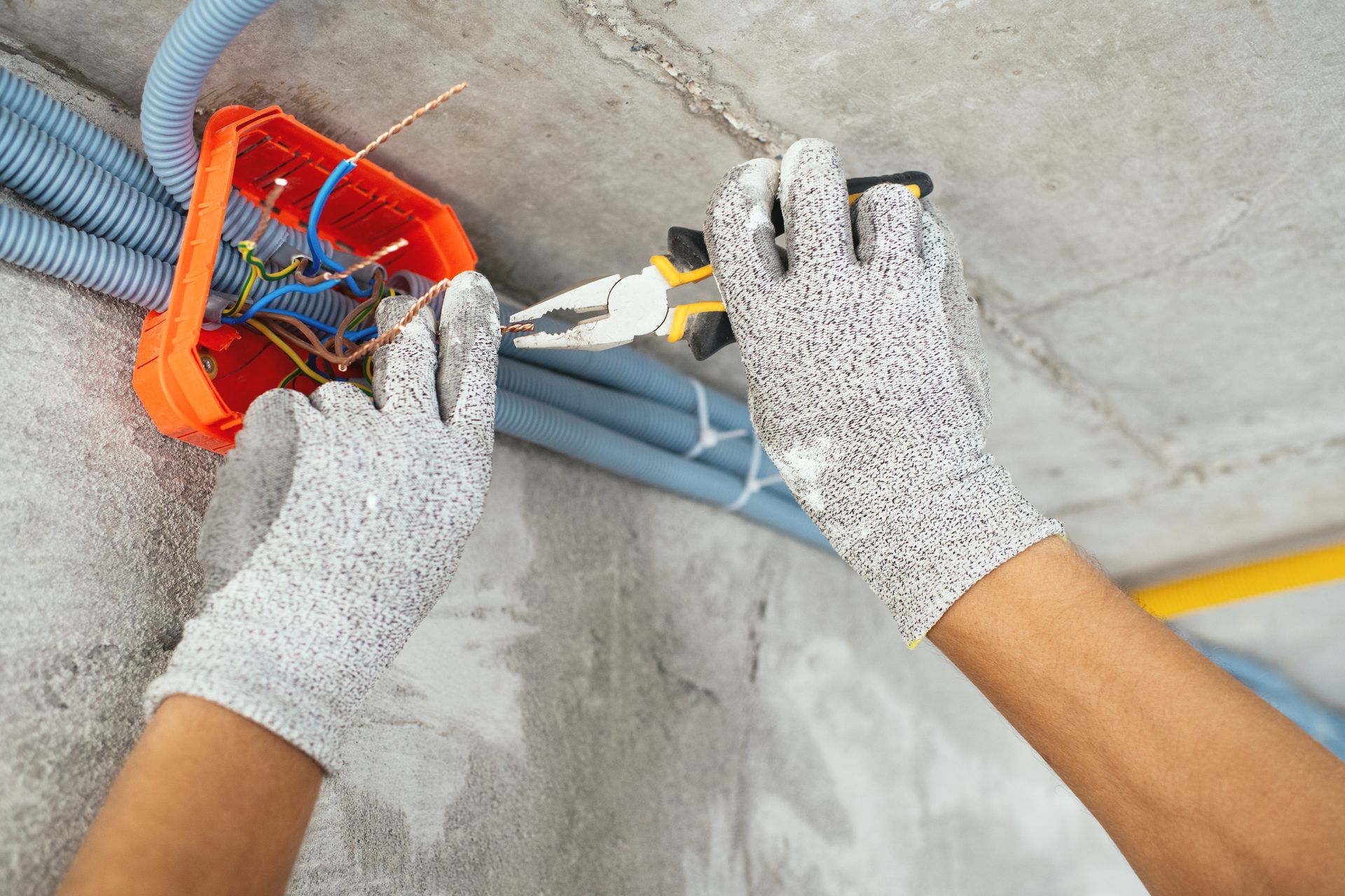 A person wearing gloves is working on electrical wires.