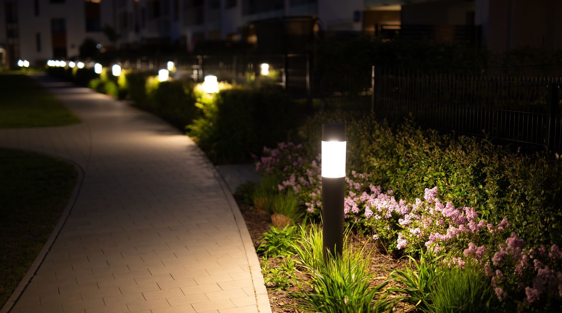 Beautiful residential patio with decorative outdoor lighting and purple lilac flowers illuminated.