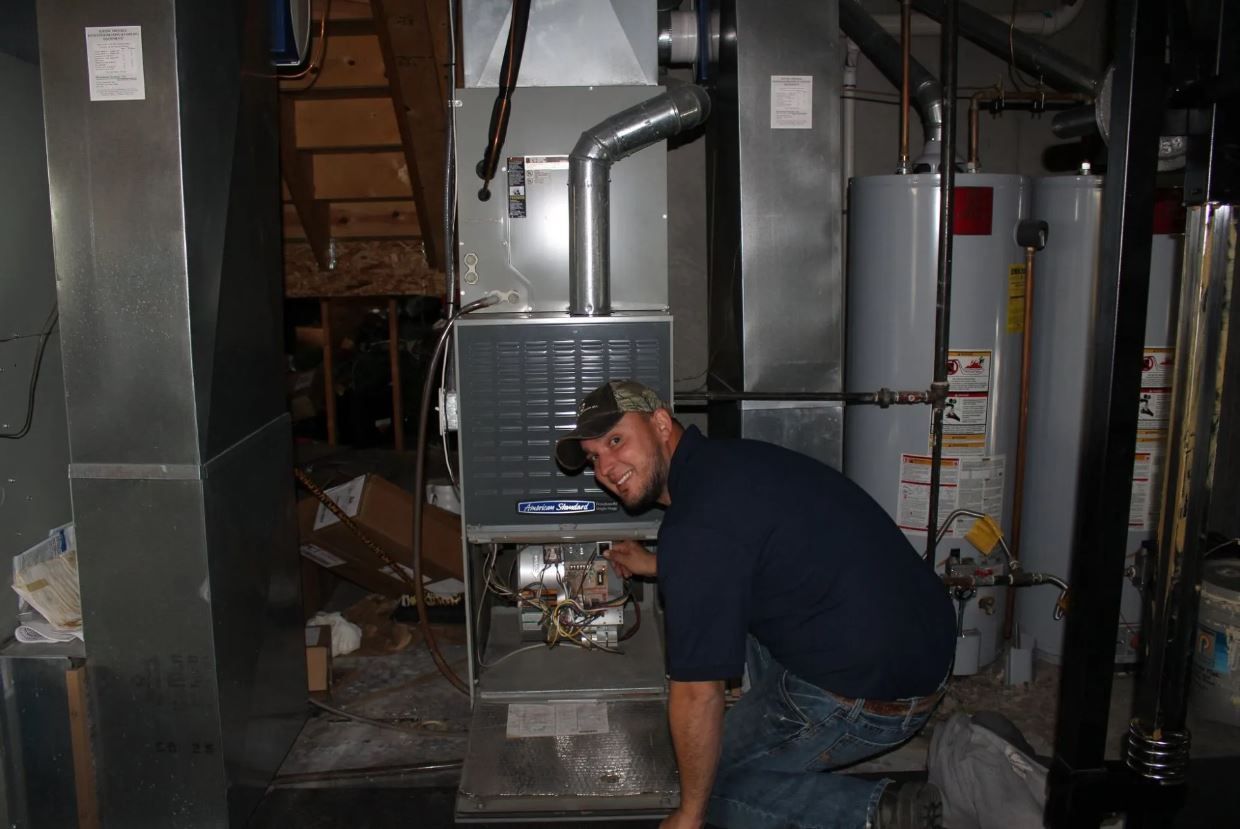 A man is working on an air conditioner in a basement.