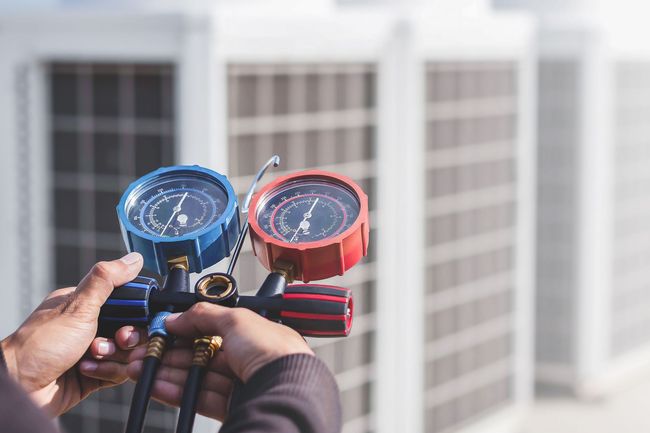A person is holding two gauges in their hands in front of a building.