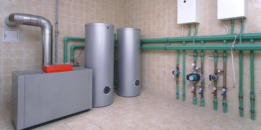 A room with two water heaters and green pipes.