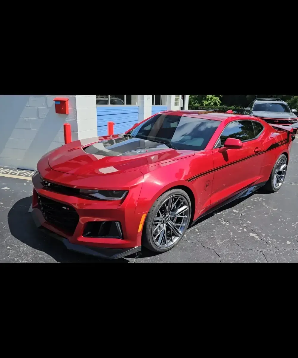 A red chevrolet camaro zl1 is parked in a parking lot.