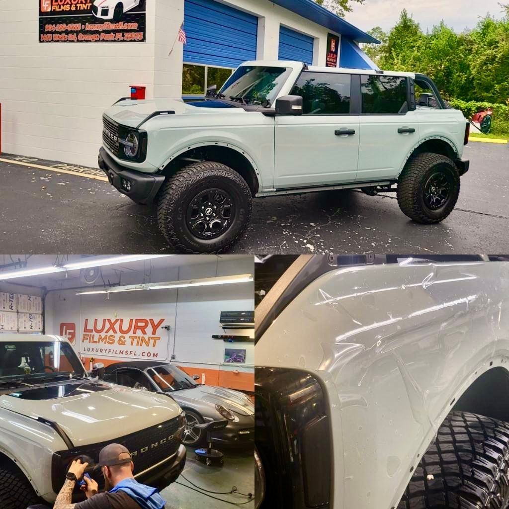 A white ford bronco is parked in front of a building.