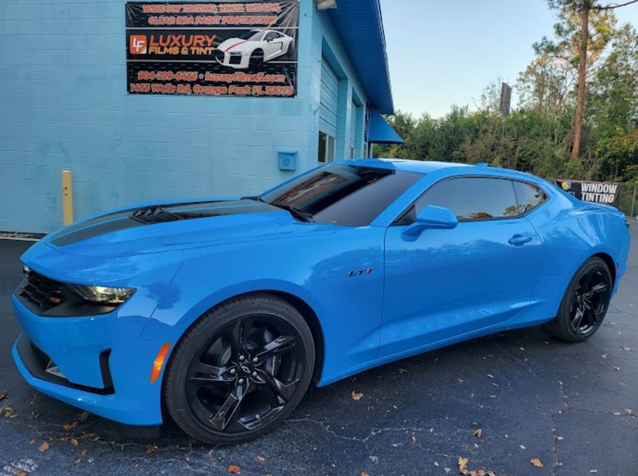 A blue car is parked in front of a blue building.