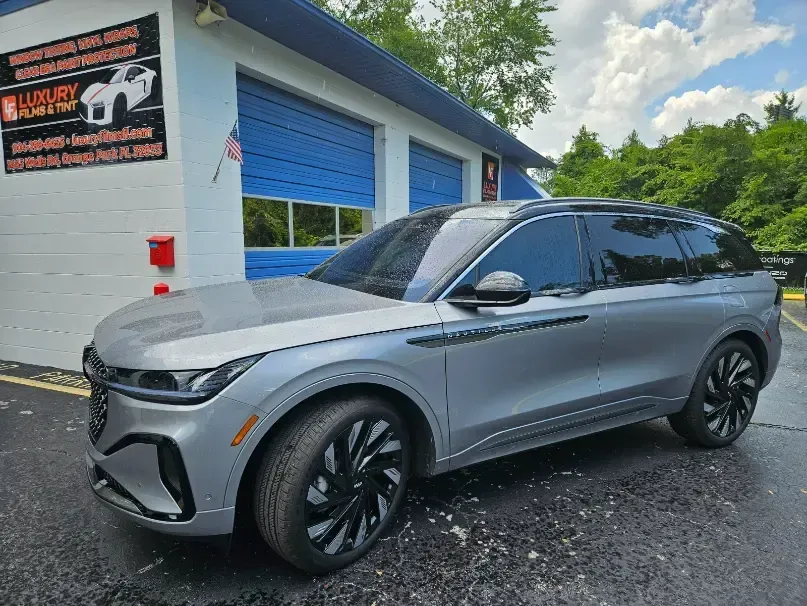 A silver car is parked in front of a garage.