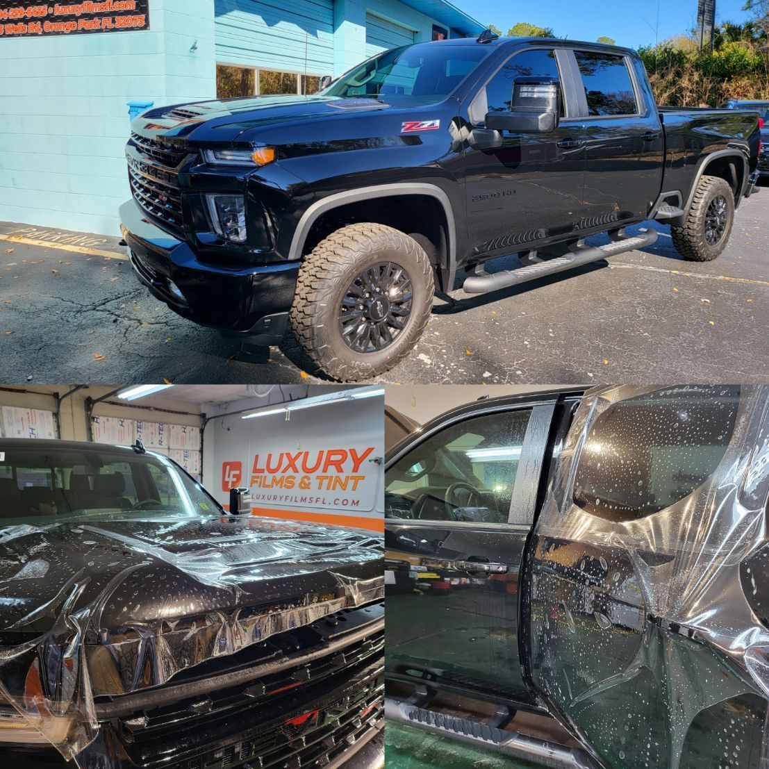 A black truck is wrapped in plastic and sitting in a parking lot.