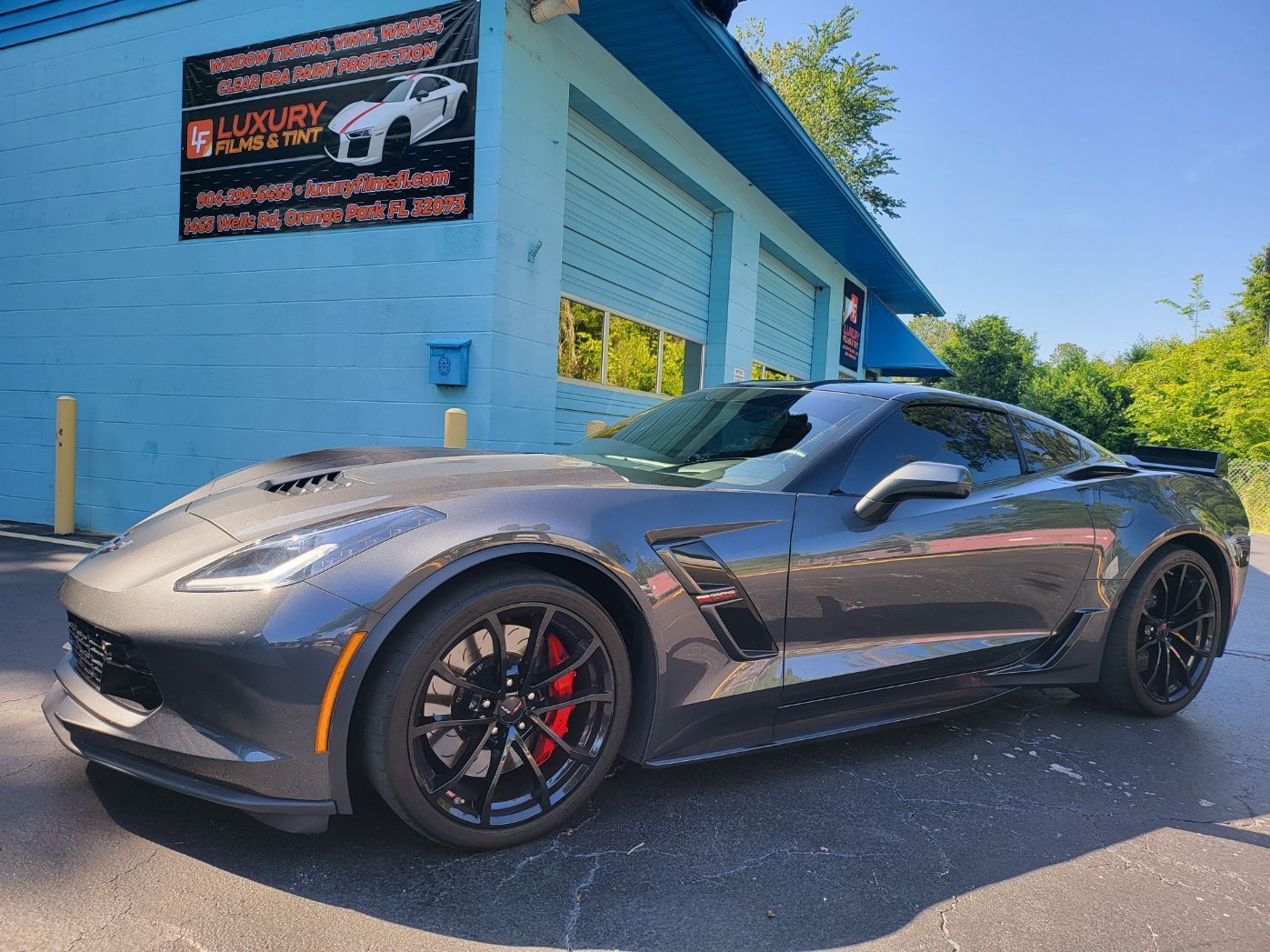 A gray sports car is parked in front of a blue building.
