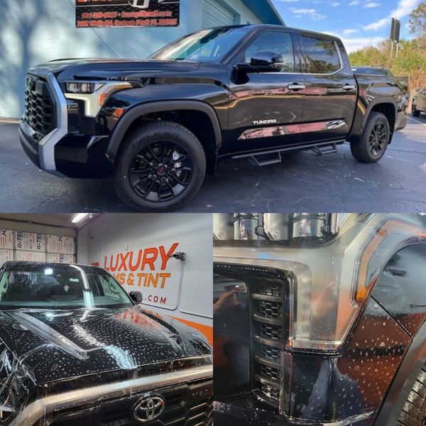 A black truck is parked in front of a luxury car tint shop
