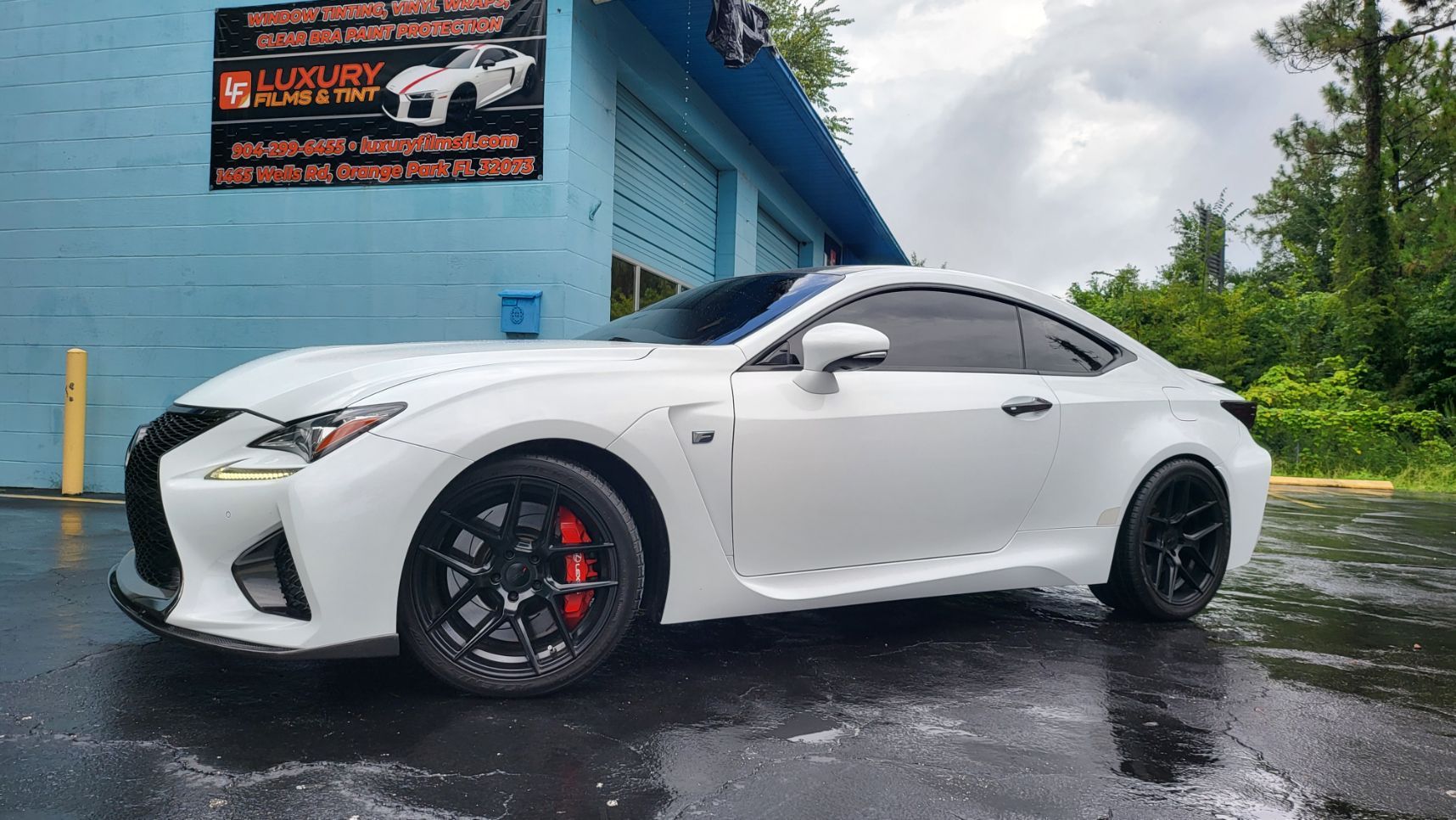 A white lexus rc is parked in front of a garage.