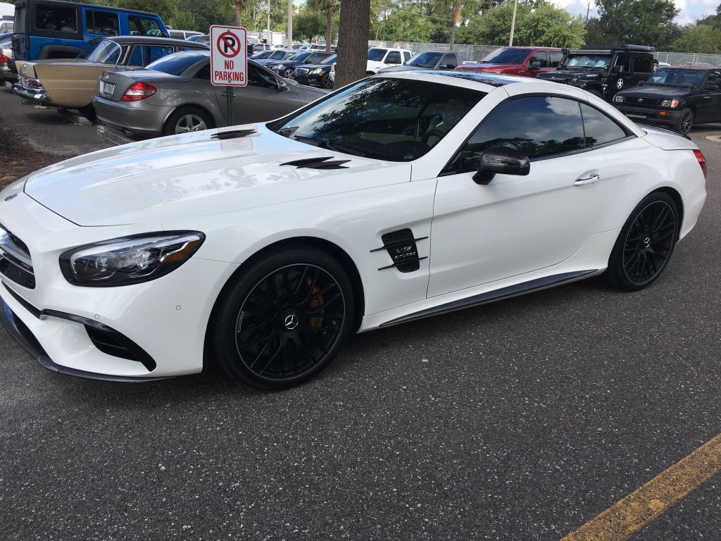 A white sports car is parked in a parking lot.