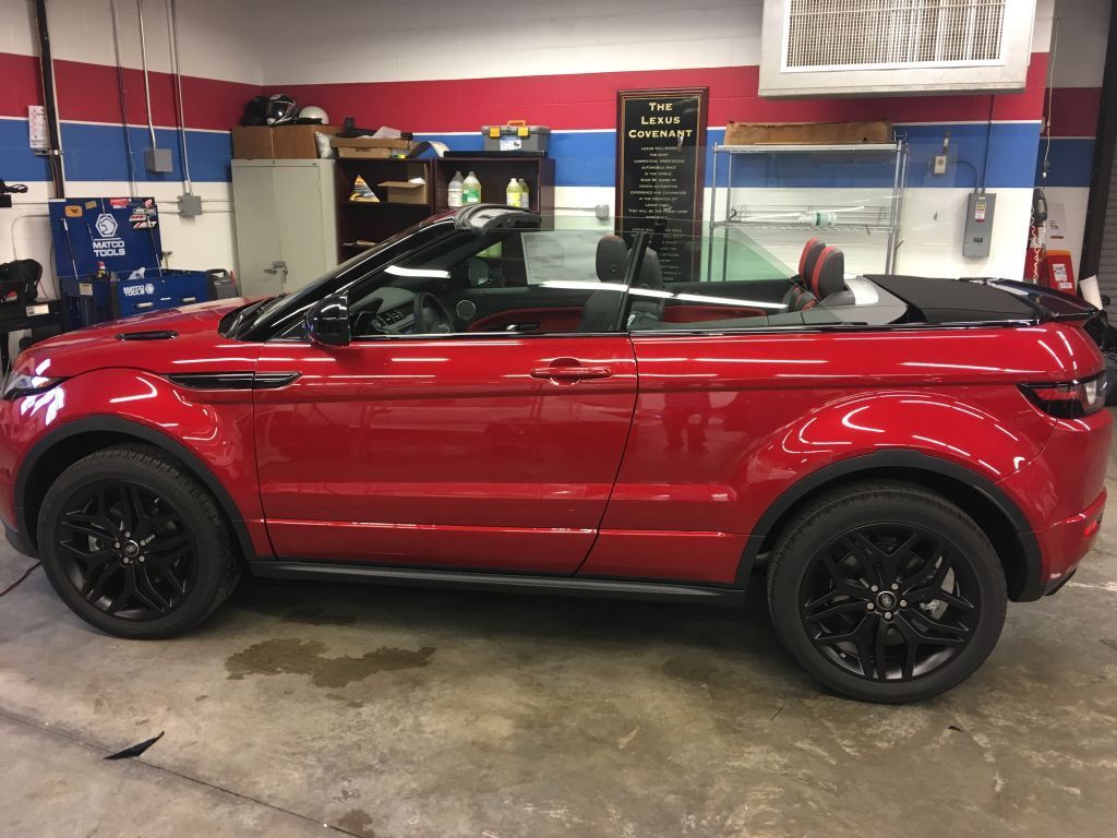 A red range rover evoque convertible is parked in a garage.