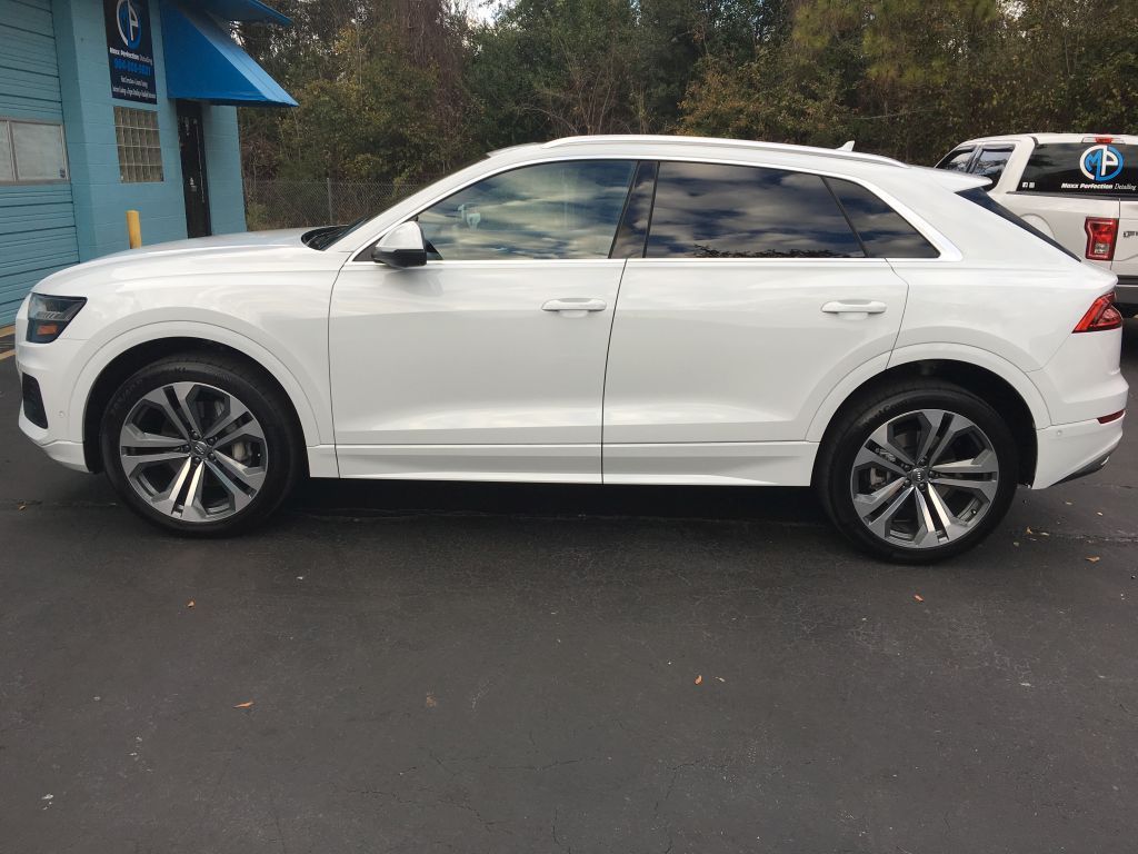 A white audi q8 is parked in a parking lot.