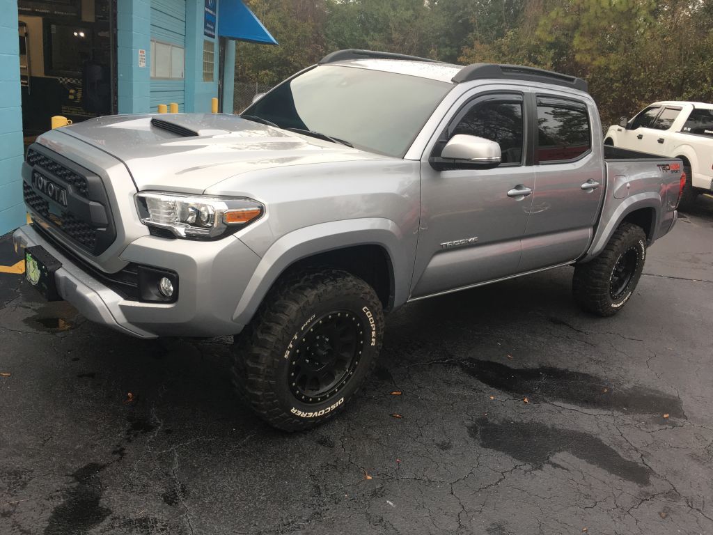 A silver toyota tacoma truck is parked in a parking lot.