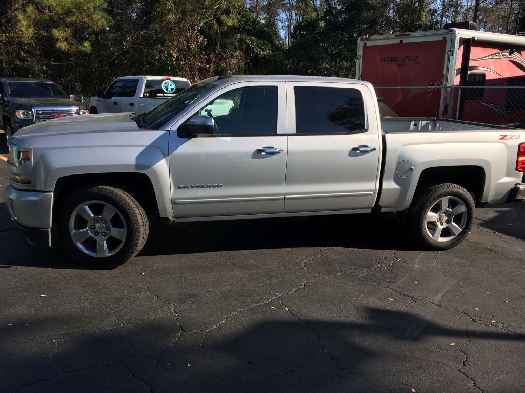 A silver pickup truck is parked in a parking lot.