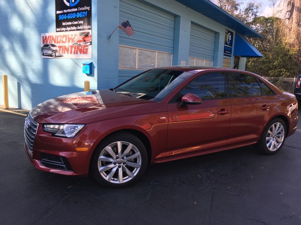A red car is parked in front of a window tinting shop