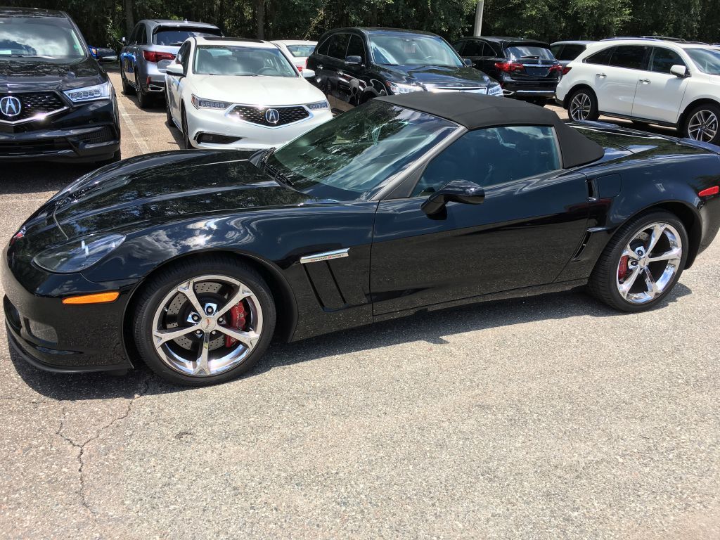 A black corvette convertible is parked in a parking lot.