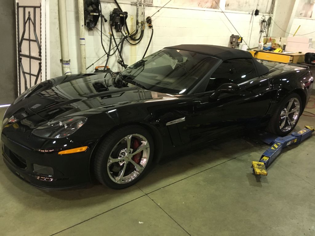 A black sports car is parked in a garage on a lift.