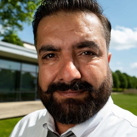 A man with a beard is wearing a white shirt and tie