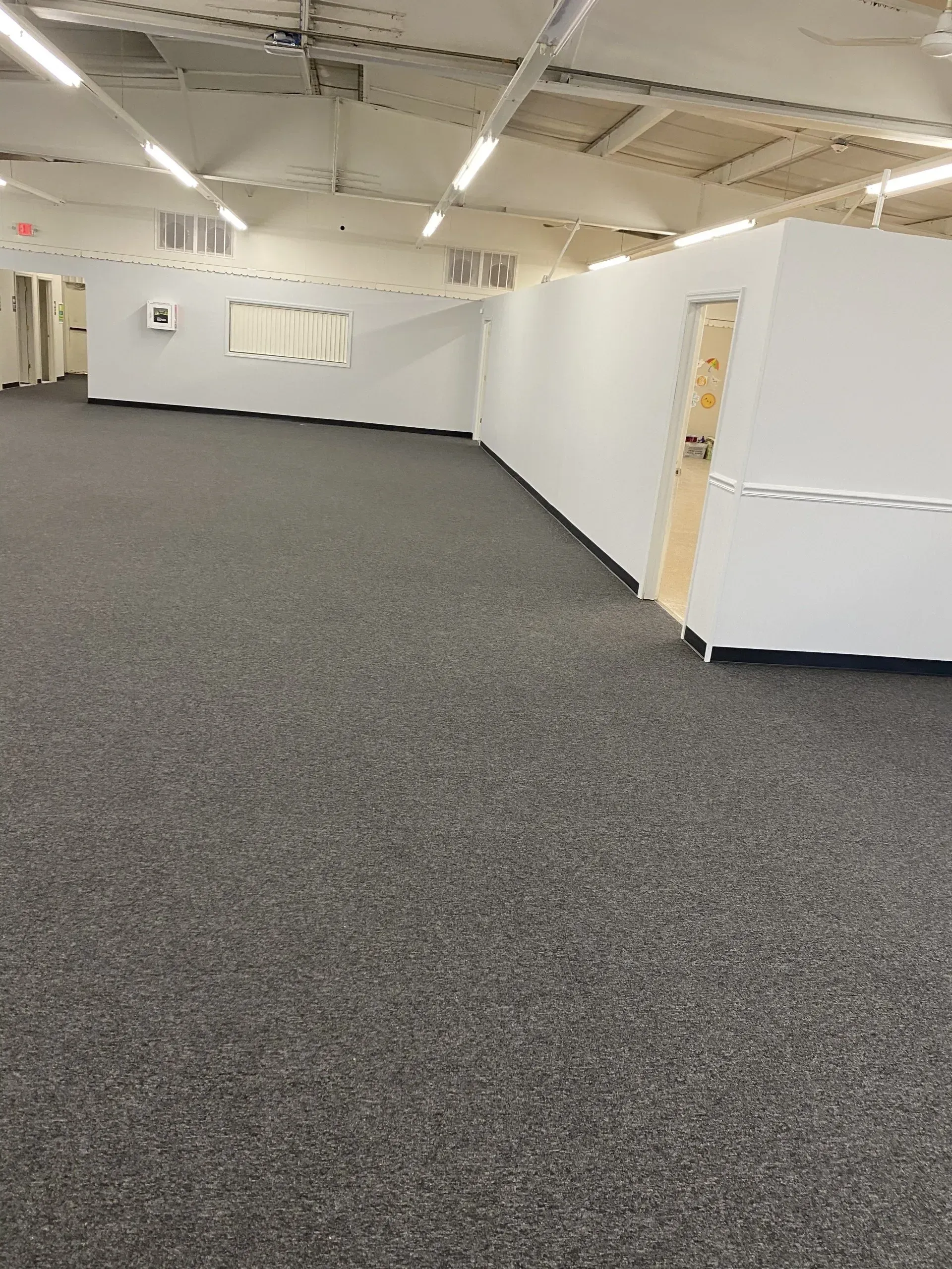A large empty room with a carpeted floor and white walls.