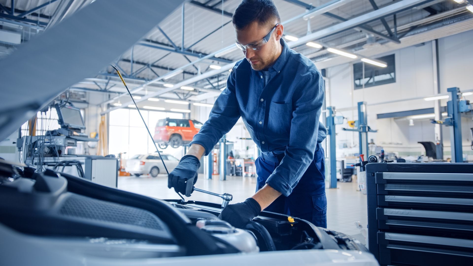 A man is working on the engine of a car in a garage.