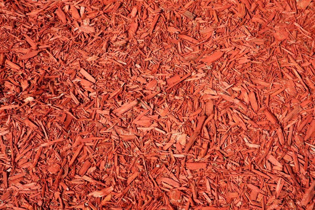 A pile of red mulch is sitting on the ground.