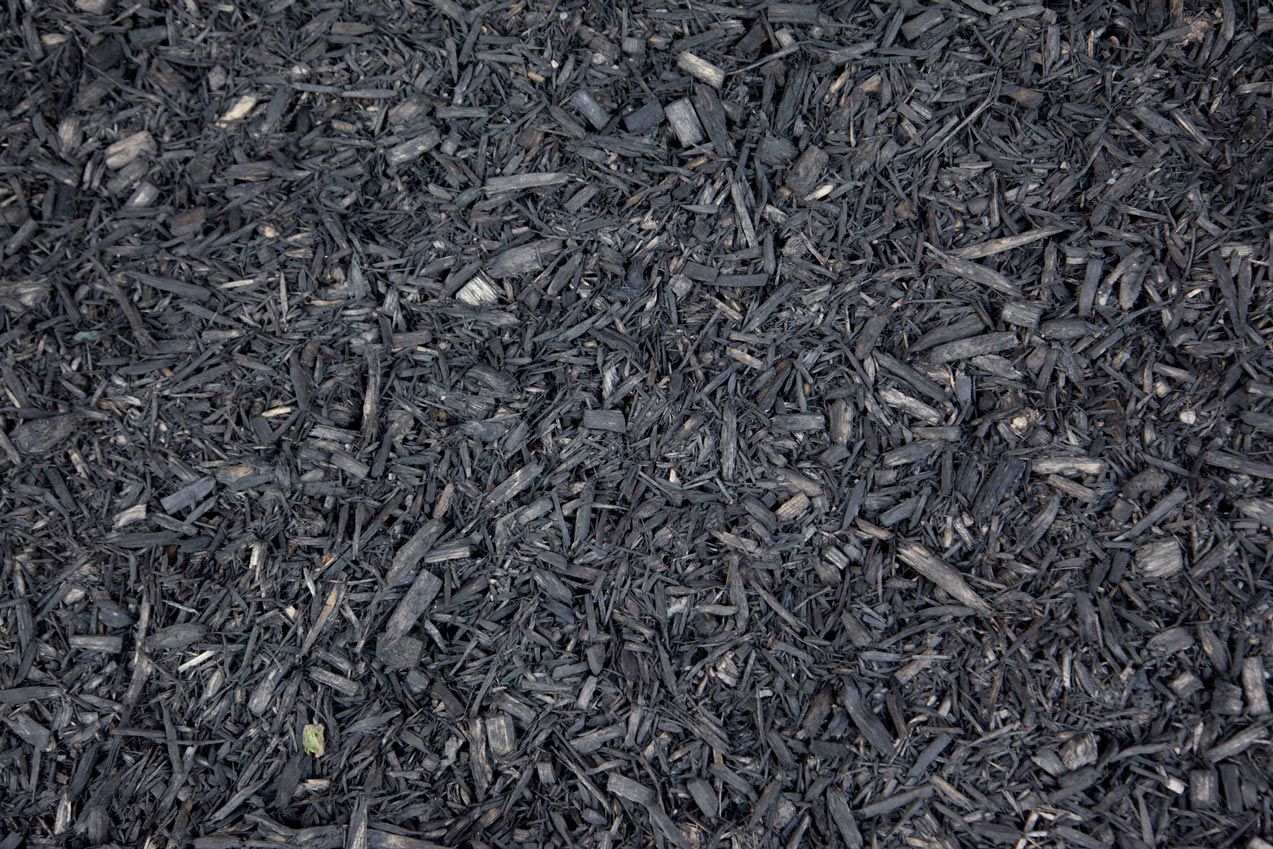 A pile of black mulch is sitting on the ground.