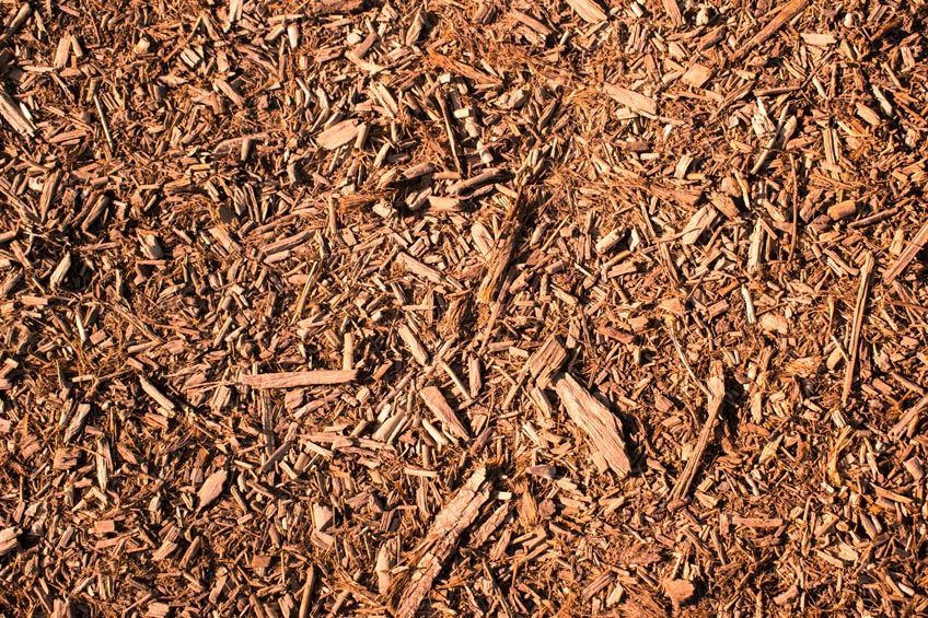 A pile of brown mulch is sitting on the ground.