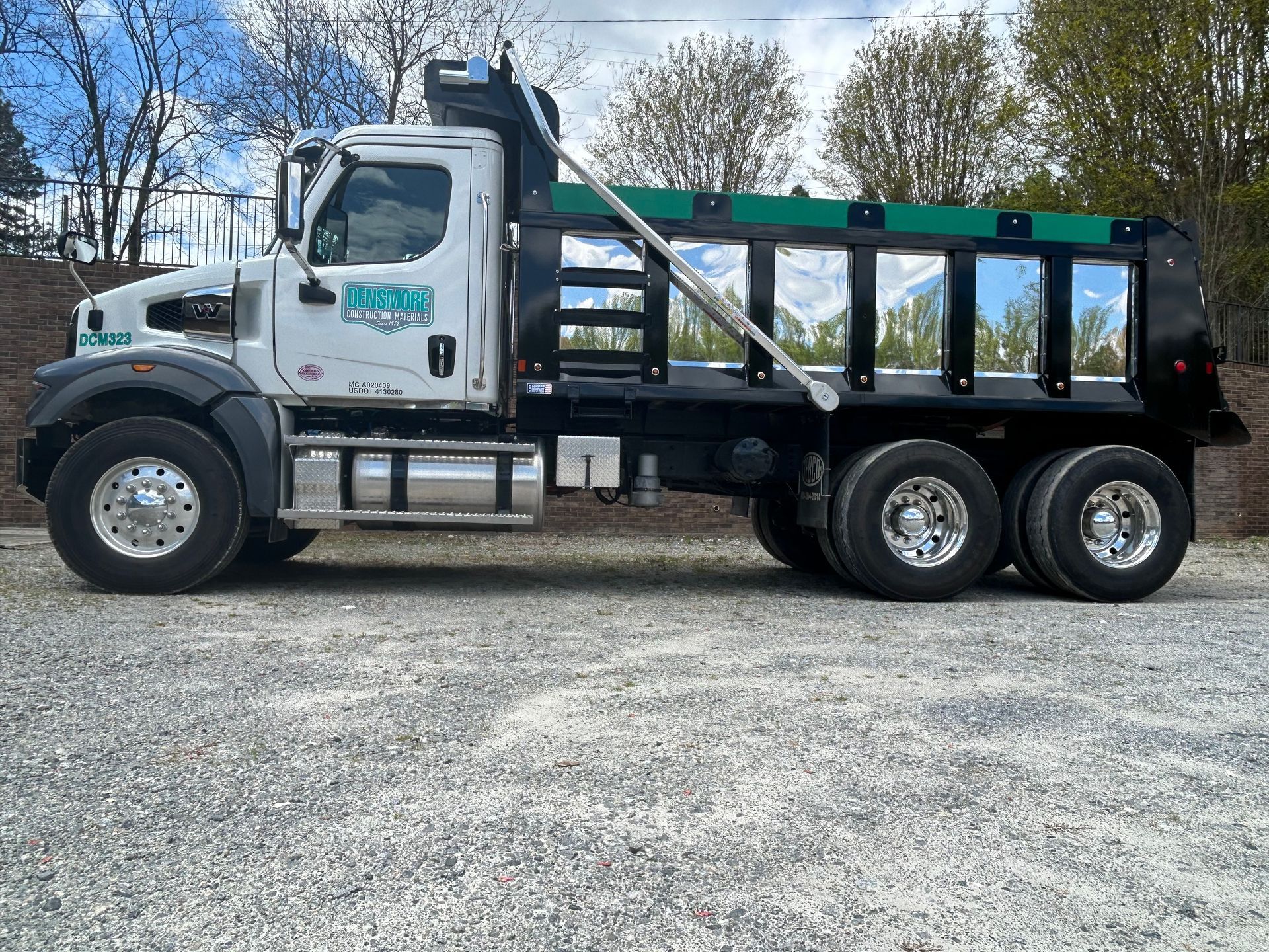 A dump truck is loading dirt into a pile.